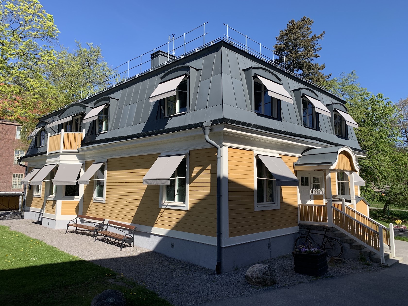 Gul trävilla med flera fönstermarkiser i solljus