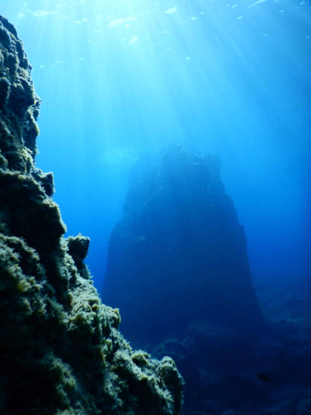 A rock wall dropping away with light coming down